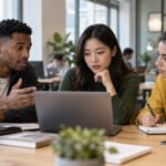 Three early-career professionals collaborating around a laptop while using AI as part of their work.